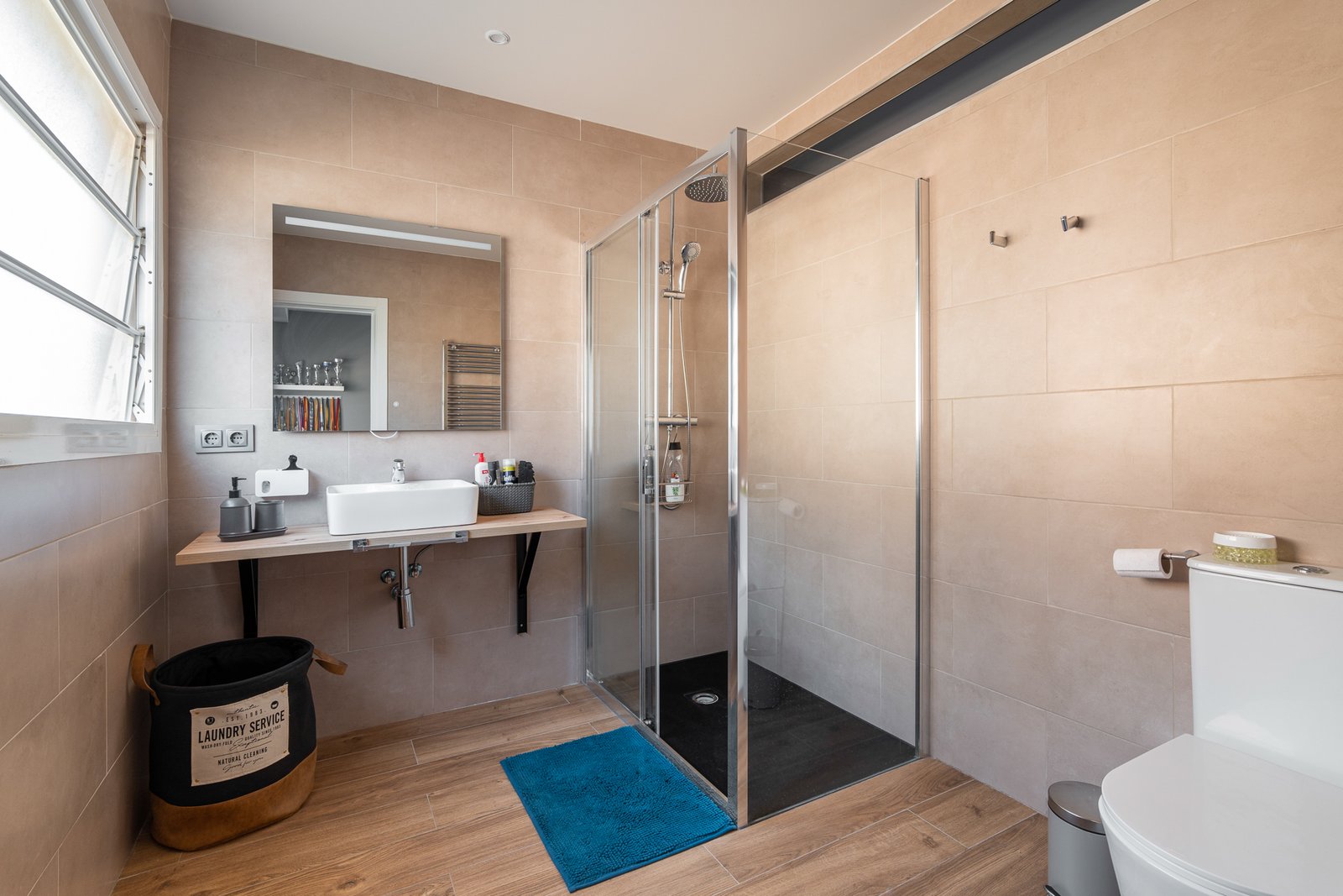 Baño terminado con estante de madera y ducha