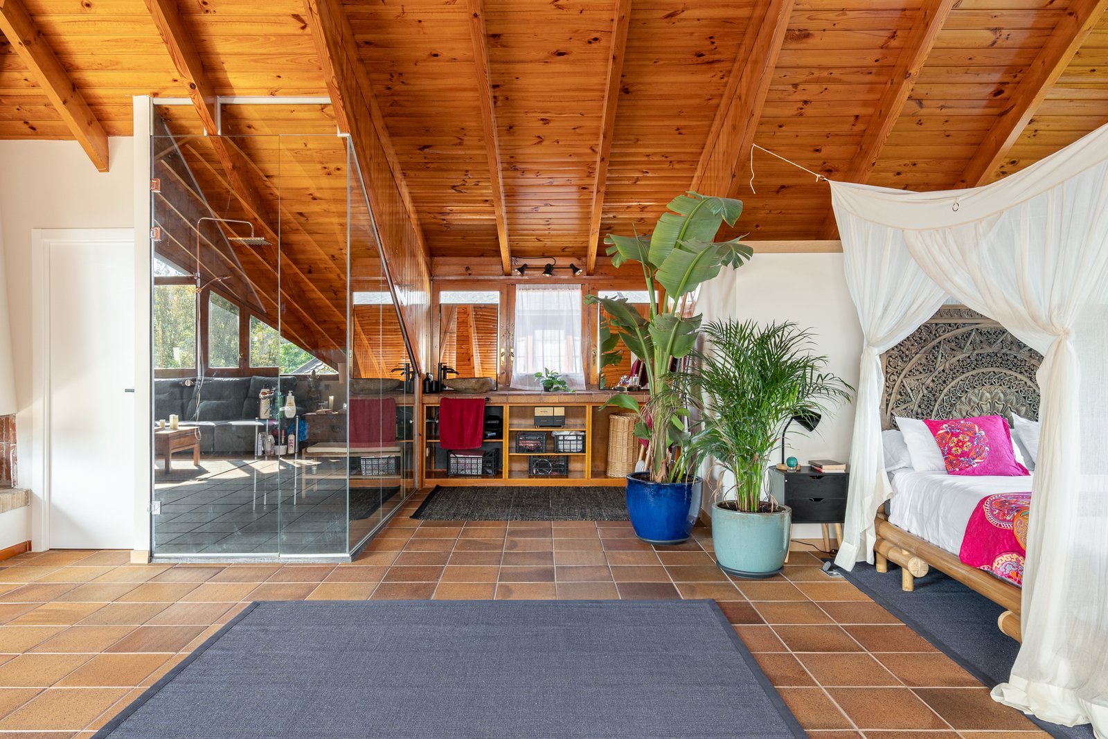 Dormitorio principal con techo de madera y cama con dosel