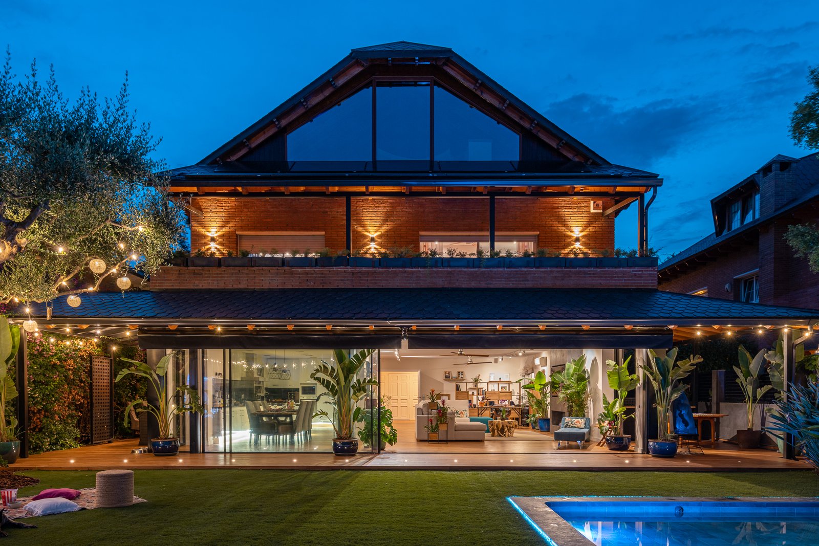Vivienda reformada con jardín y piscina iluminada al atardecer
