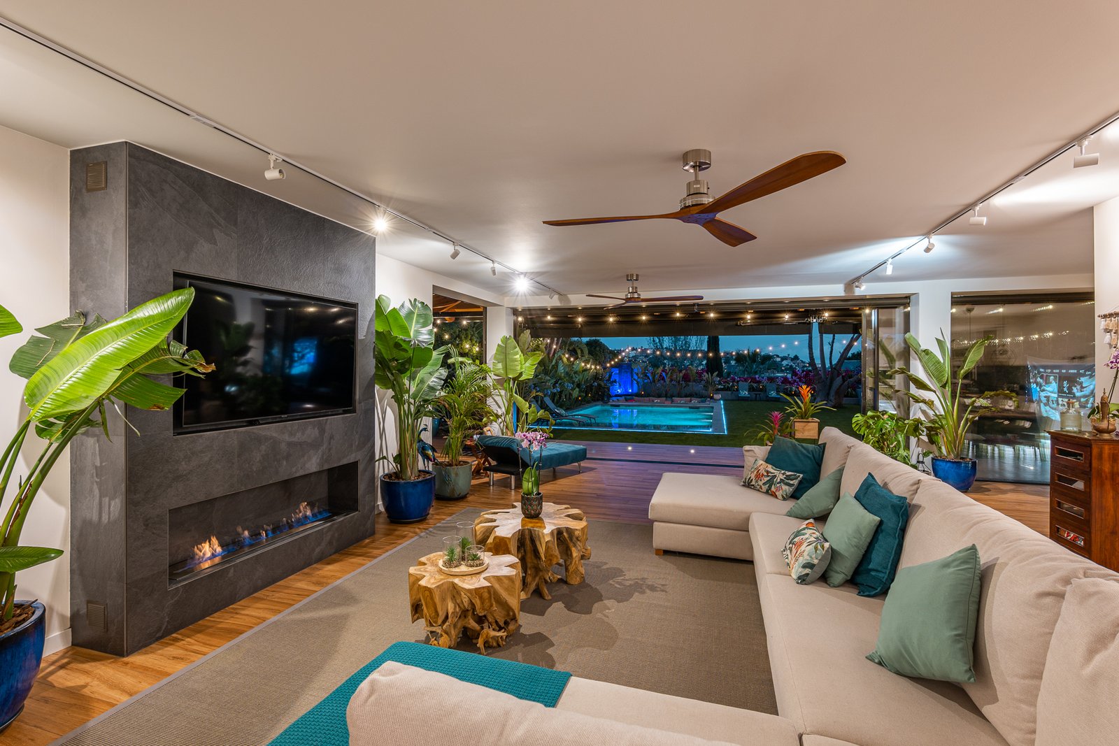 Salón abierto con chimenea y vistas a la piscina, de noche